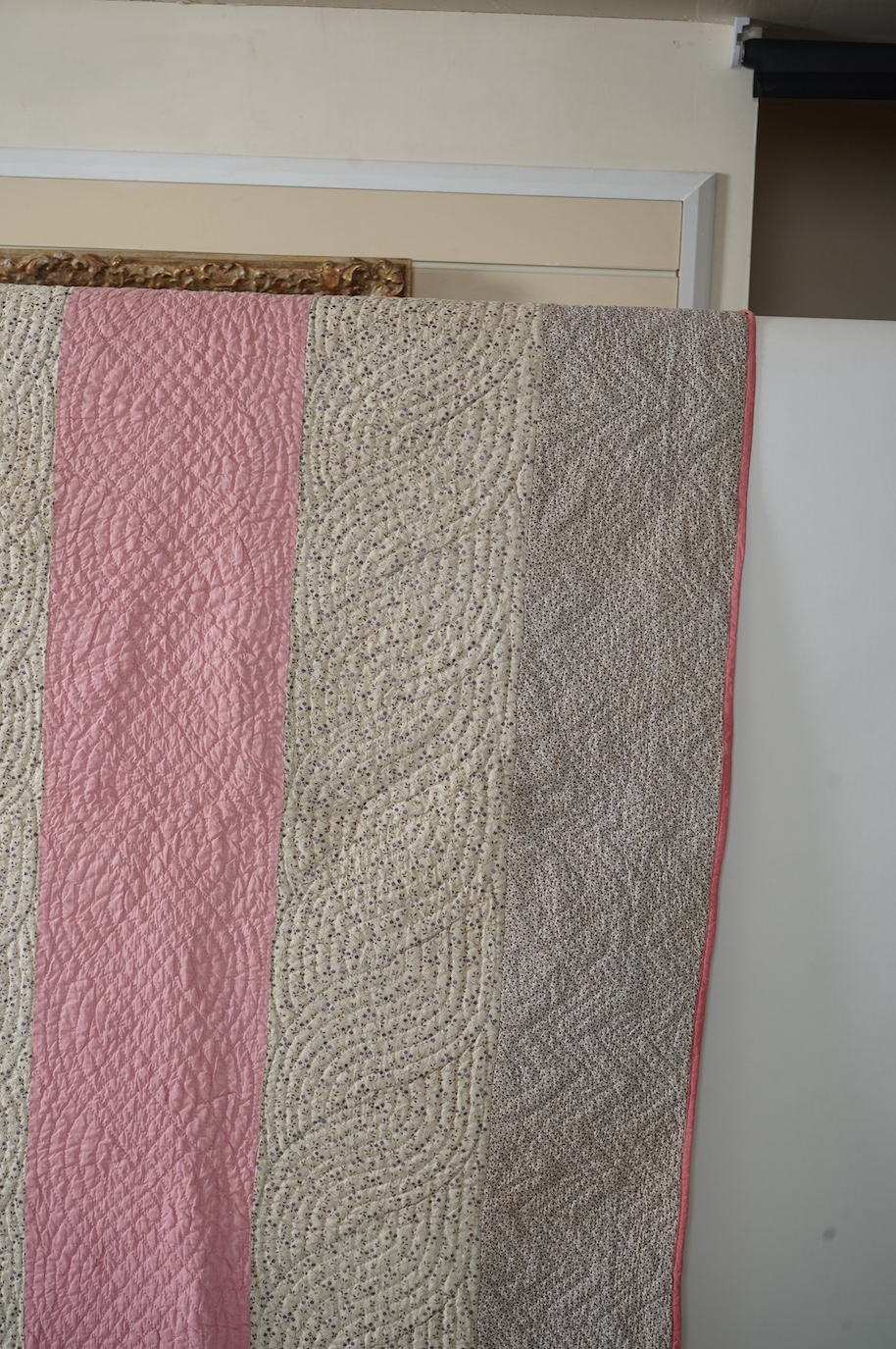 An English 19th century, highly ornate hand quilted English bedcover. Designed using alternating stripes, in a plain pink and a small printed floral cotton, then finishing with two borders of a darker minute spot floral